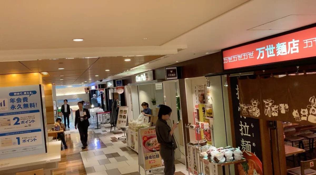 Concourse of a multi-tenant Japanese commercial building, with shopfronts along both sides of a walkway