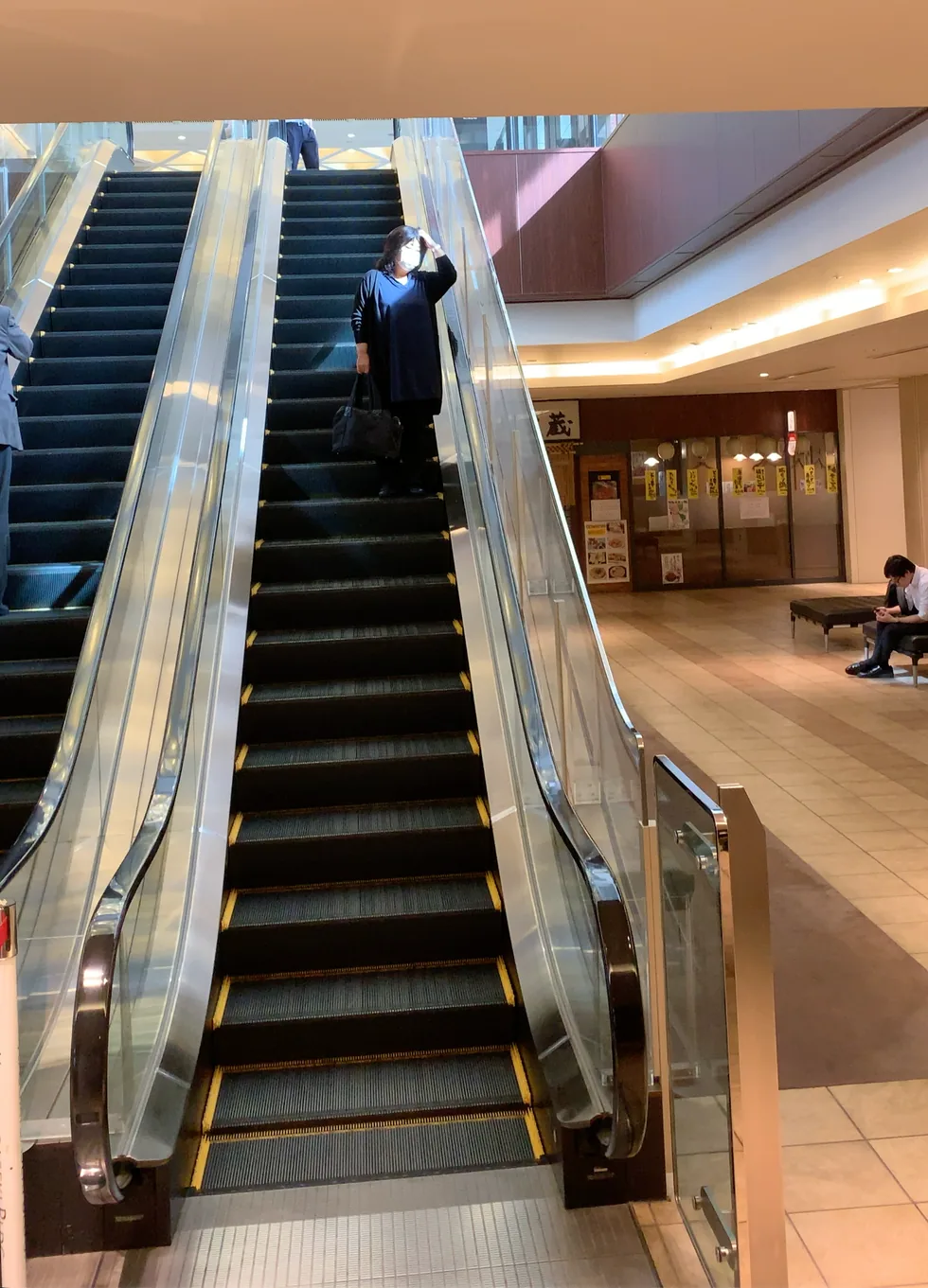 Escalators rising between floors of a Japanese commercial building, the kind of scene used for directional people-flow measurement