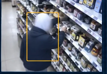 An example store camera frame with a detection box drawn around a shopper at a shelf
